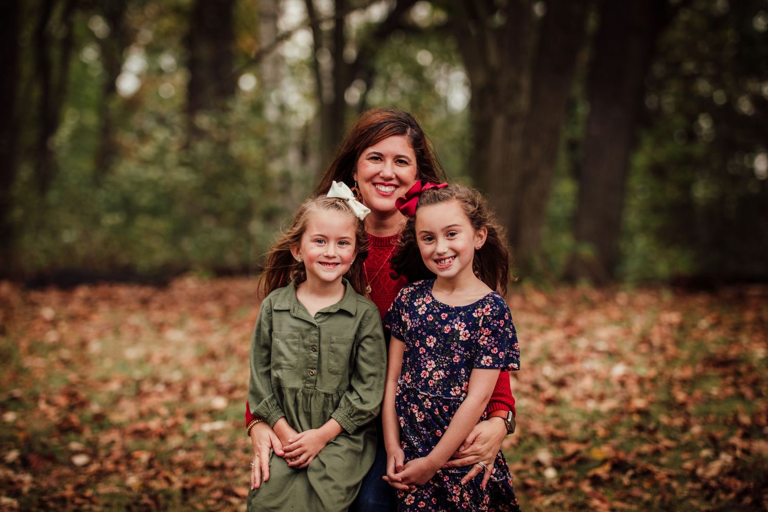 Family portrait in autumn forest with fallen leaves.