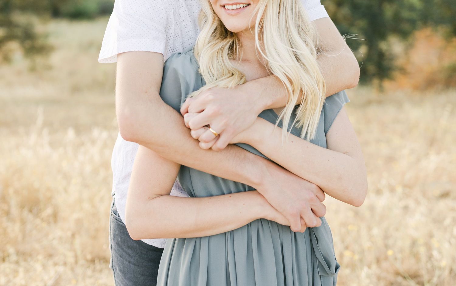 A tender embrace captured in a sunlit field of golden grass during sunset.
