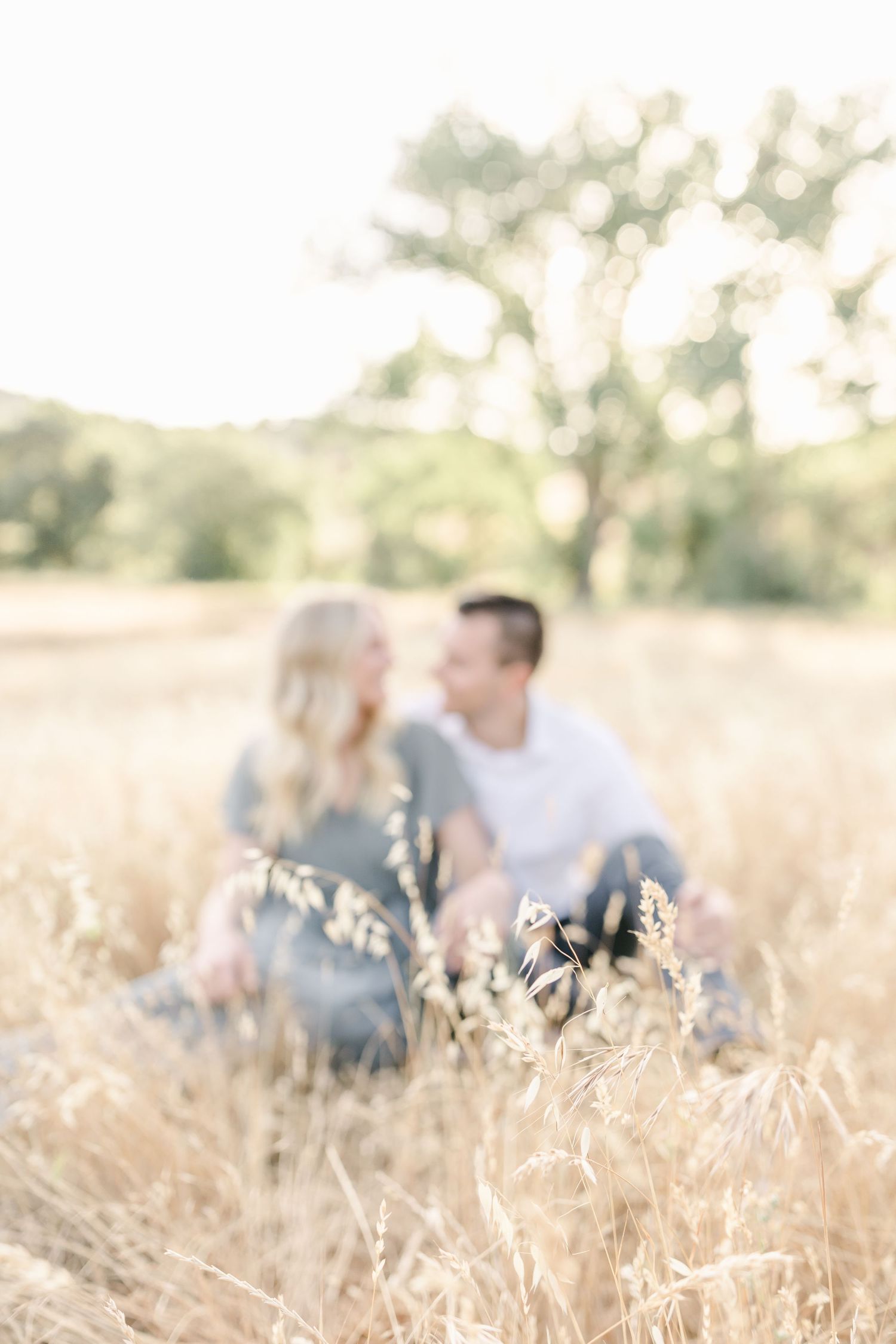 Soft focus romantic portrait in a golden wheat field with sunlit background and ethereal summer afternoon lighting.