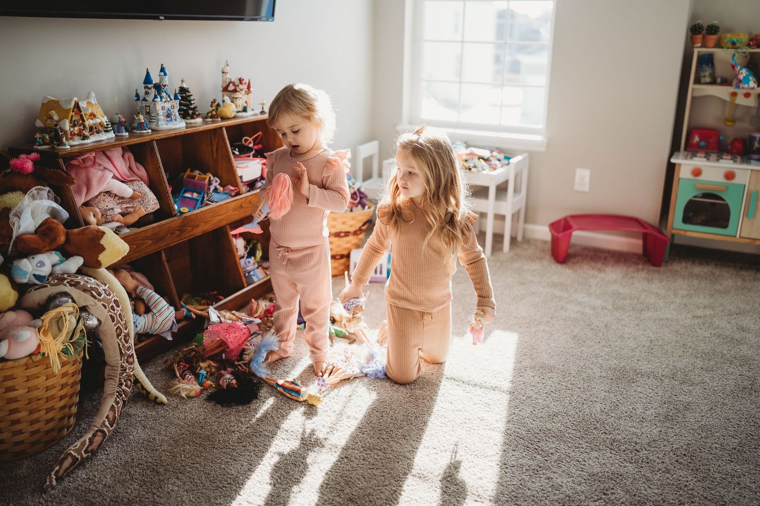 Family playfully wrestling and relaxing together on a grey couch in a sunny living room.