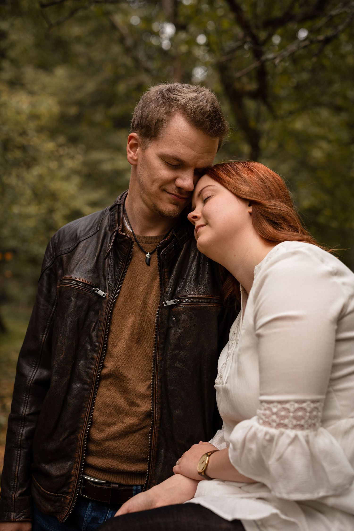 Man and woman leaning at each other with their eyes closed.