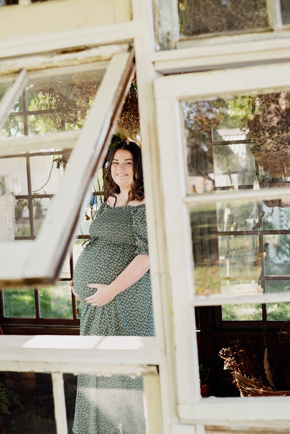 Person in polka dot dress looking through vintage greenhouse windows.