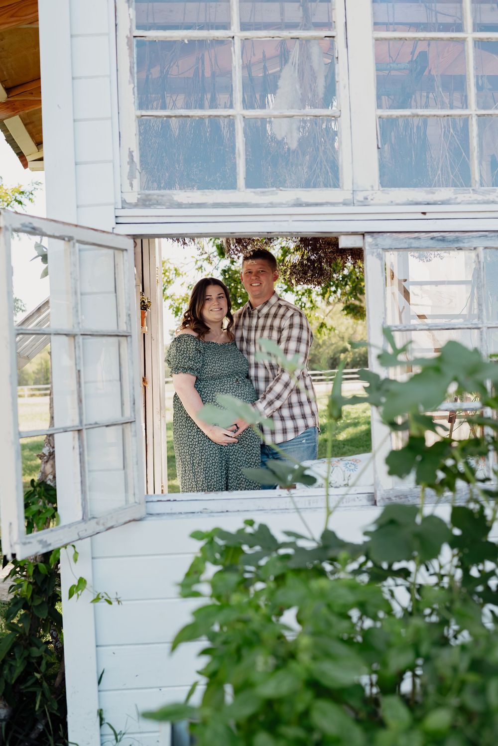 Couple sharing tender moment by rustic greenhouse windows.