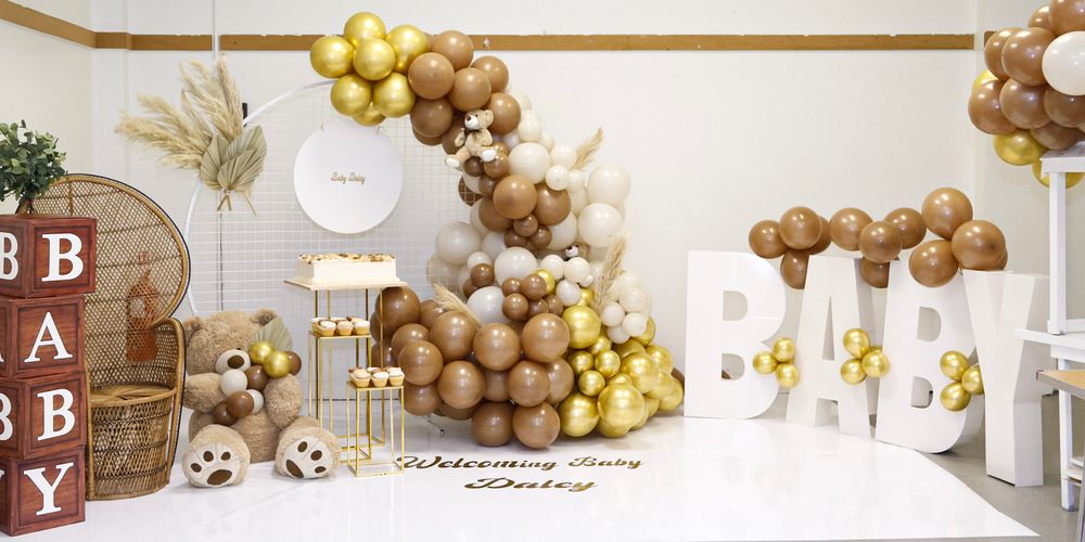 Modern event space decorated with gold and brown balloon garlands and white accents.