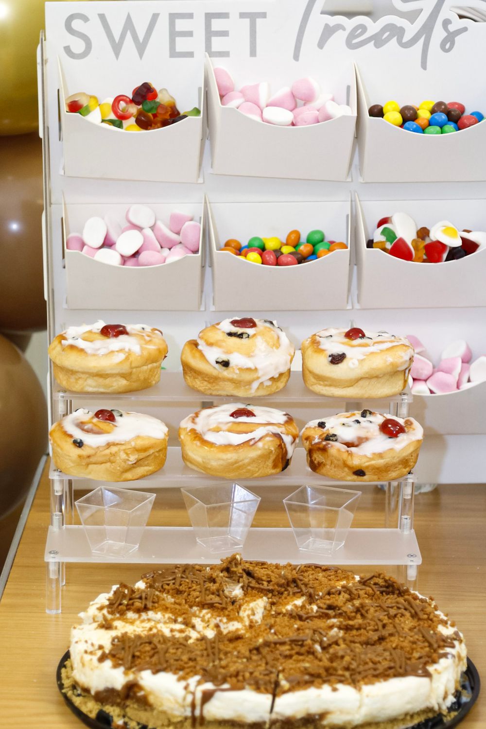Dessert table with pastries and sweets display featuring 'Sweet Treats' signage.