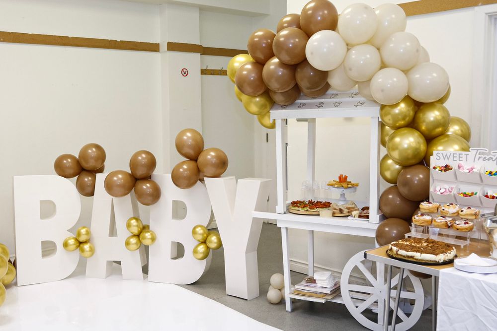 Modern event space decorated with white and gold balloon arrangements and tables.