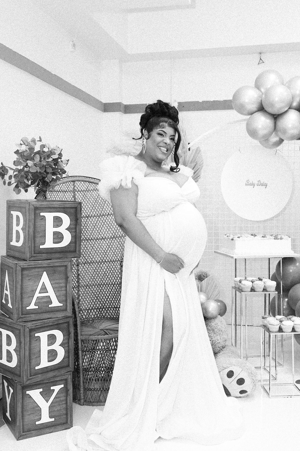 Black and white maternity photo with decorative BABY blocks and balloon arrangements.