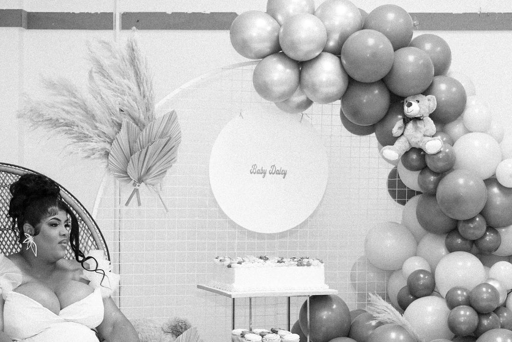 Elegant maternity photoshoot setup with balloon arch and pampas grass decorations.