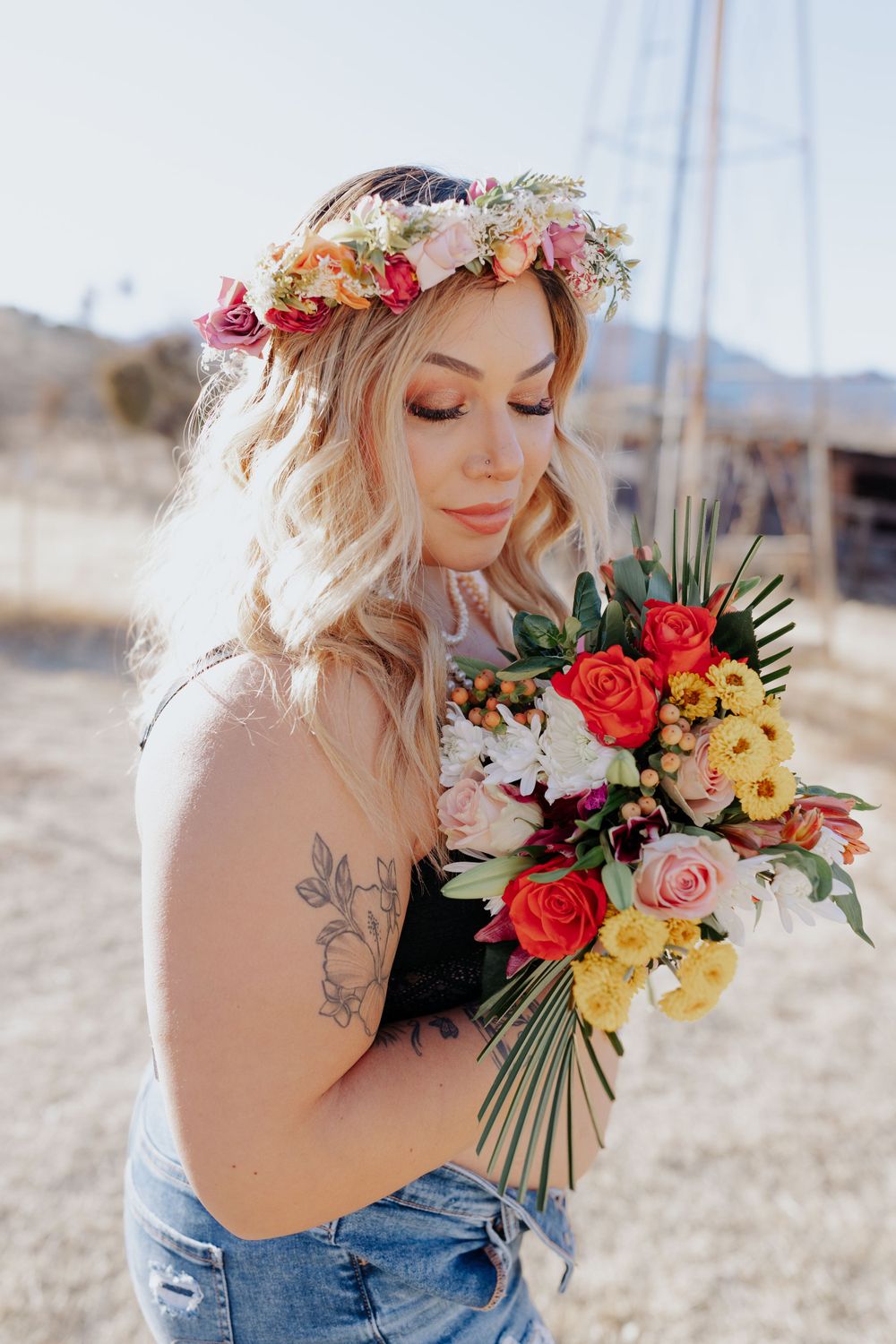 A bright bouquet of roses and wildflowers complements a floral crown in a desert setting.