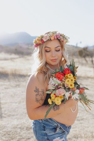 A delicate floral crown and vibrant bouquet create a romantic desert portrait.