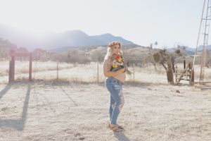 Desert landscape photoshoot with rustic wooden fence and dried grass in background.