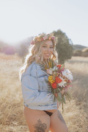 Sun-drenched outdoor portrait with denim jacket and floral accessories.