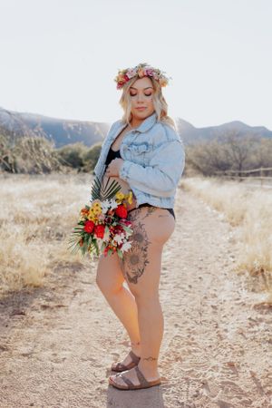 Desert maternity session featuring floral crown, denim jacket and colorful wildflower bouquet.
