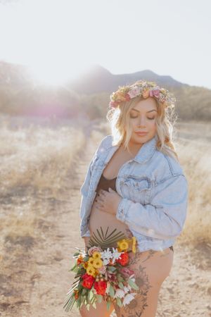 Ethereal desert maternity photos with sunlit mountains and vibrant floral arrangements.