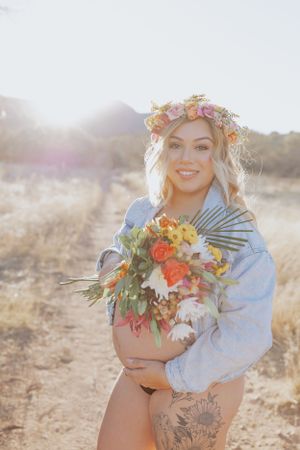 Dreamy maternity portrait with light-filled desert landscape and bright floral bouquet.