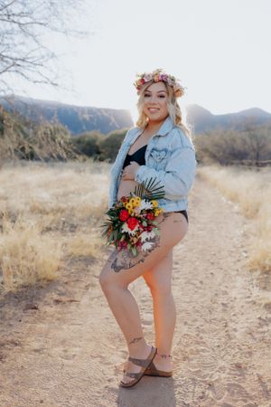 Desert landscape maternity portrait with denim and floral accessories.