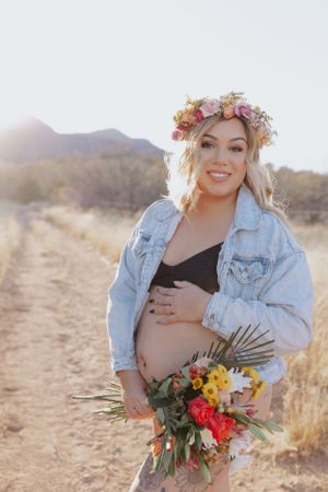 Bohemian maternity session with flower crown and denim jacket in desert setting.