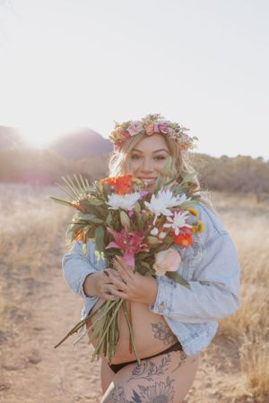 Soft-lit desert maternity portrait with vibrant floral arrangement and crown.