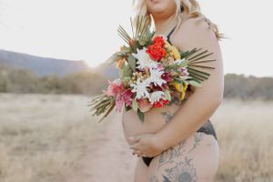 Desert maternity photoshoot featuring delicate floral arrangements and natural lighting.