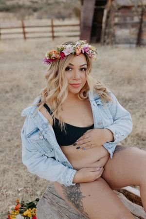 Artistic maternity photos in a rustic desert setting with denim jacket and flower crown.