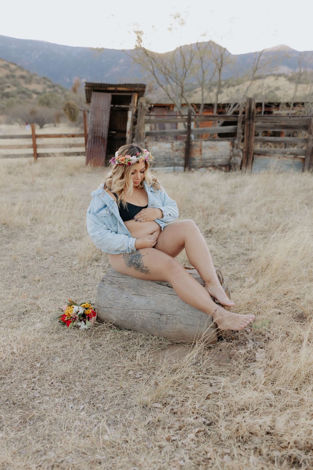 Dreamy desert maternity session with mountains and old wooden structures in background.