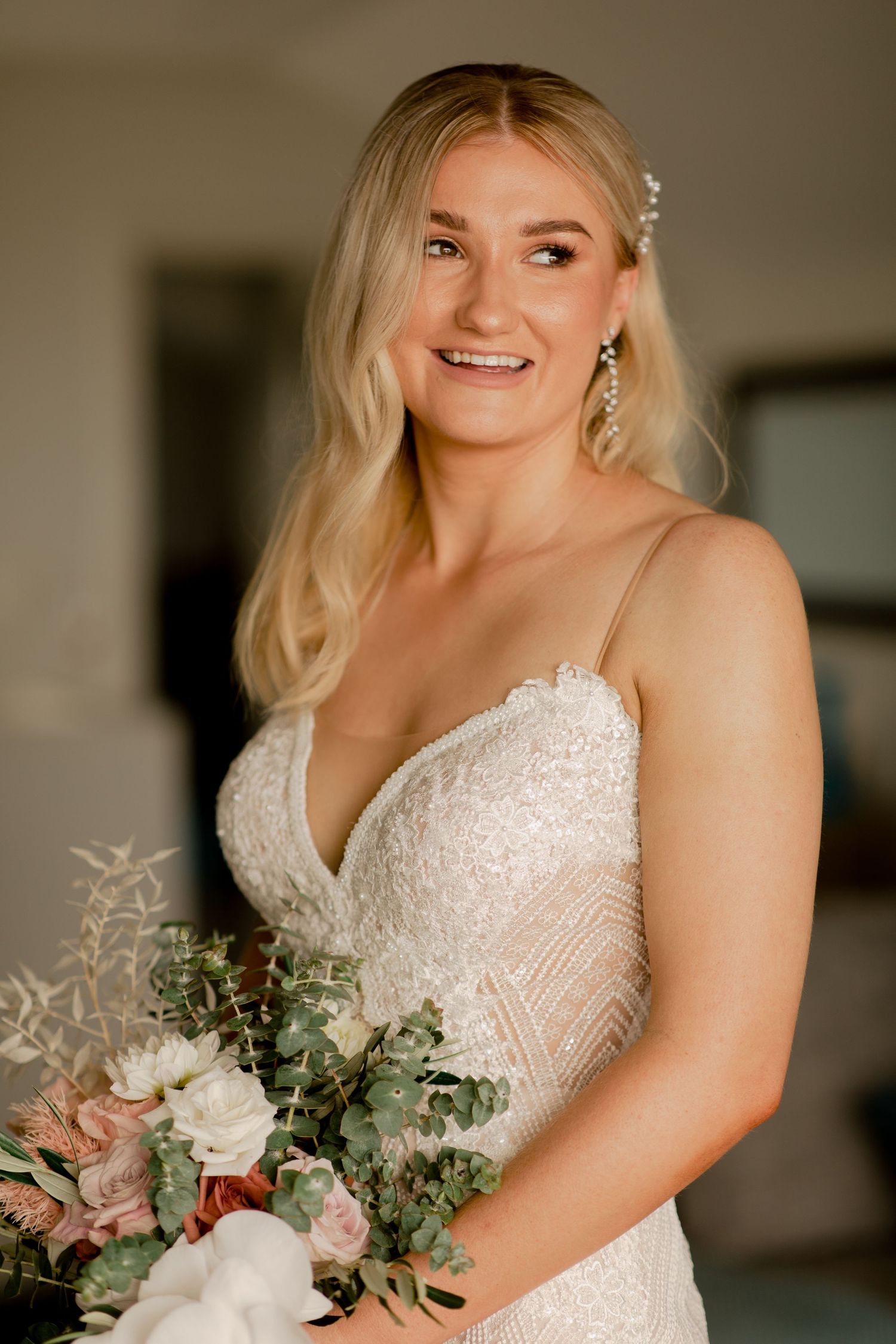 Elegant bride holds a white and pink bouquet while wearing a lace wedding gown.