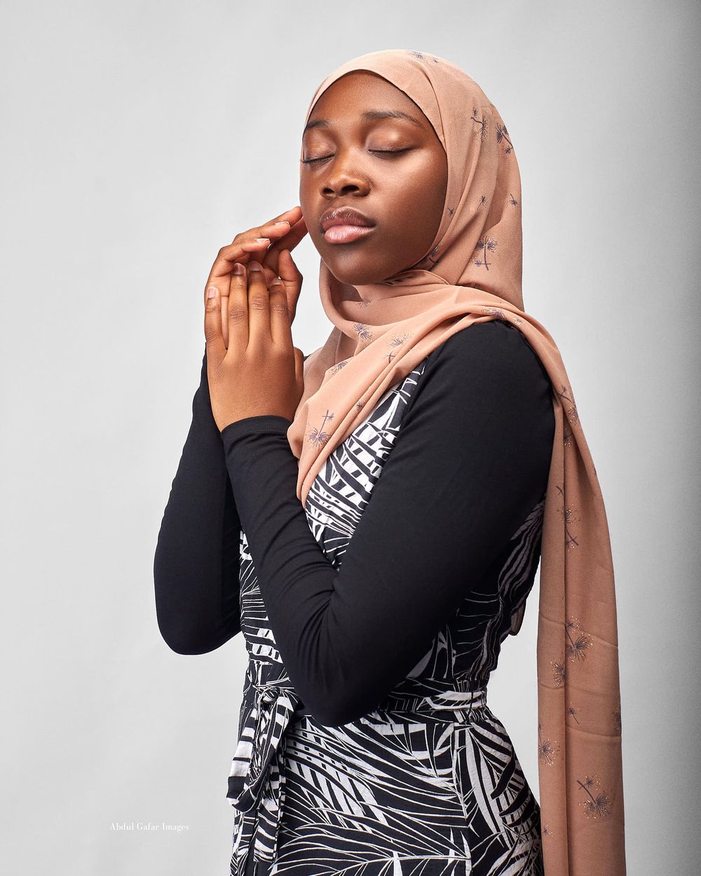 Portrait of a beautiful Hijabi resting her eyes with hands to a side of her face and posing with elegance.