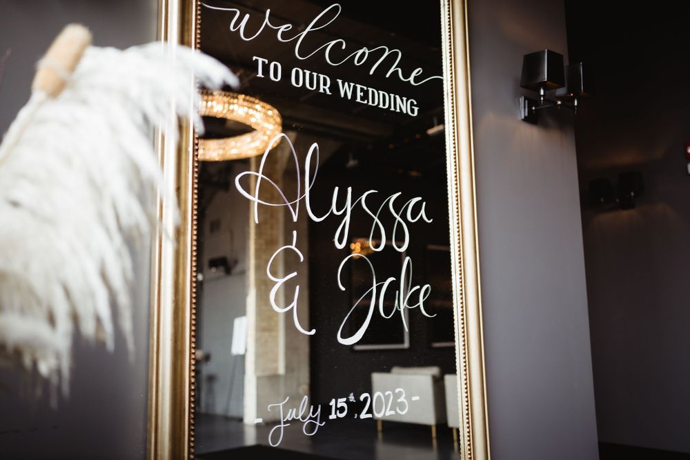 Elegant wedding welcome sign with calligraphy displayed in gold frame.