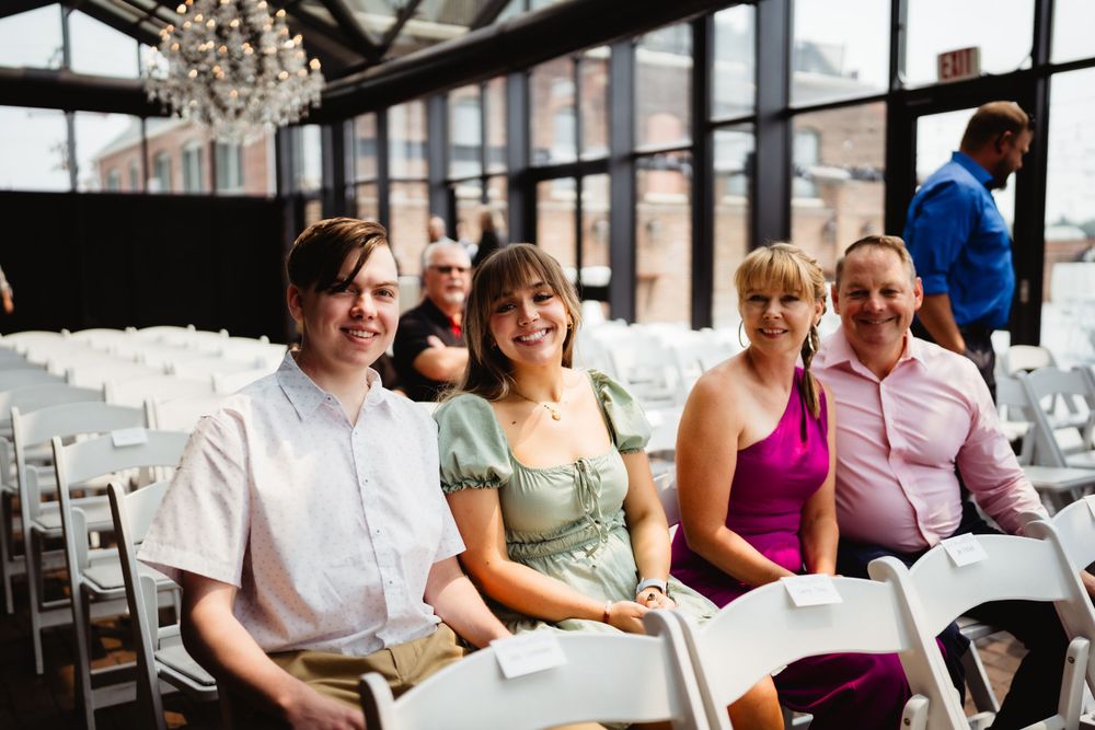 Wedding guests seated in rows during ceremony with elegant chandelier overhead.