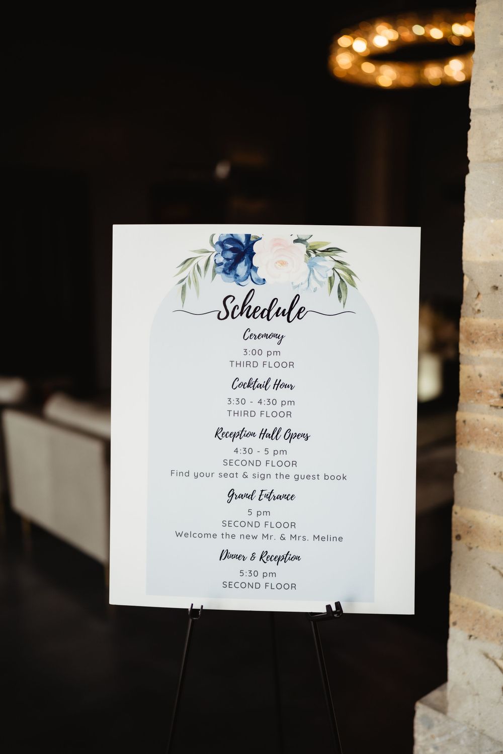 Wedding schedule card with blue floral watercolor design displaying ceremony and reception details.