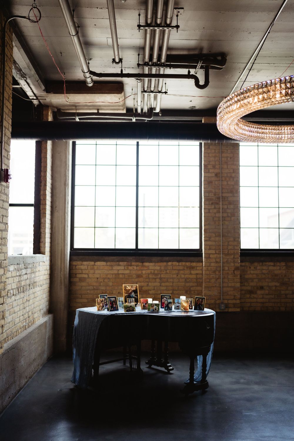 Industrial reception space with exposed brick walls and decorative table setting under modern lighting fixtures.