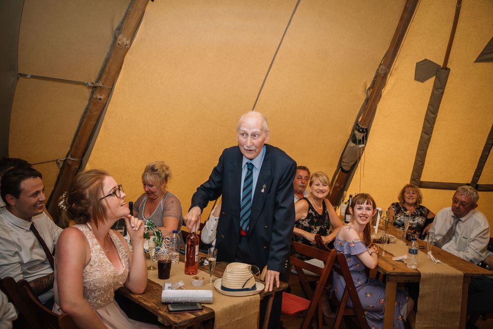 Wedding guests enjoying speeches and toasts during an indoor reception celebration.