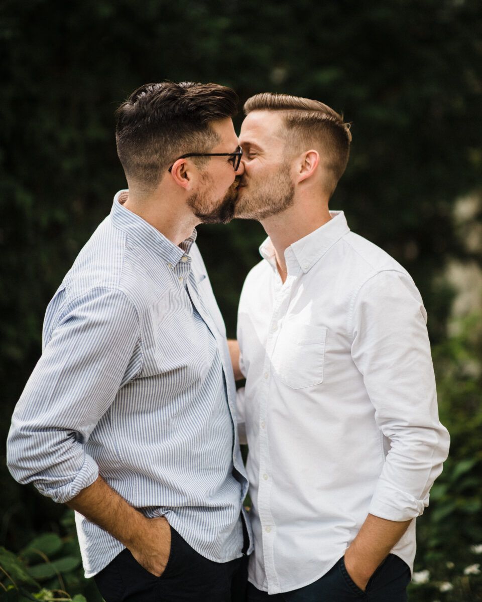 Two people in white shirts sharing an intimate conversation outdoors.
