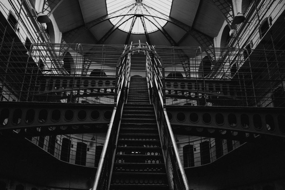 Symmetrical prison interior showing multiple levels with metal railings and staircases.