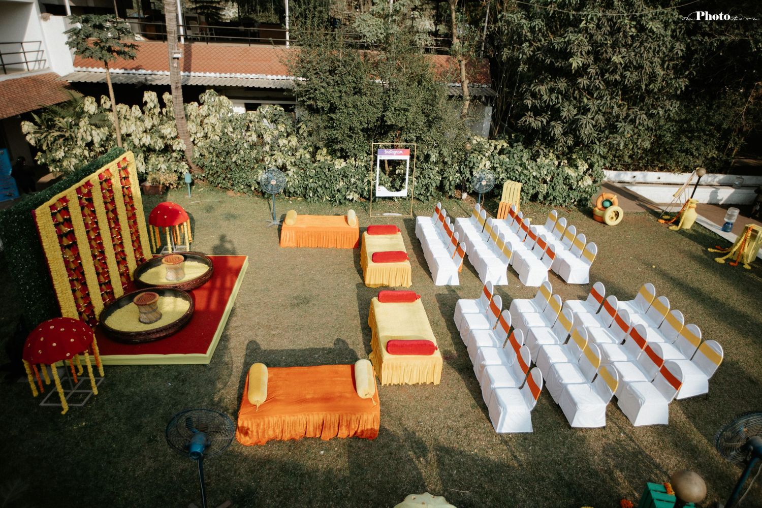 Wedding ceremony setup with white chairs and orange accents in a rustic outdoor venue.