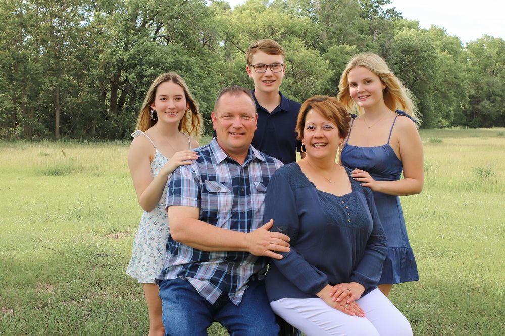 becky katzberg photography family summer photo in a grassy field with tall trees in the background