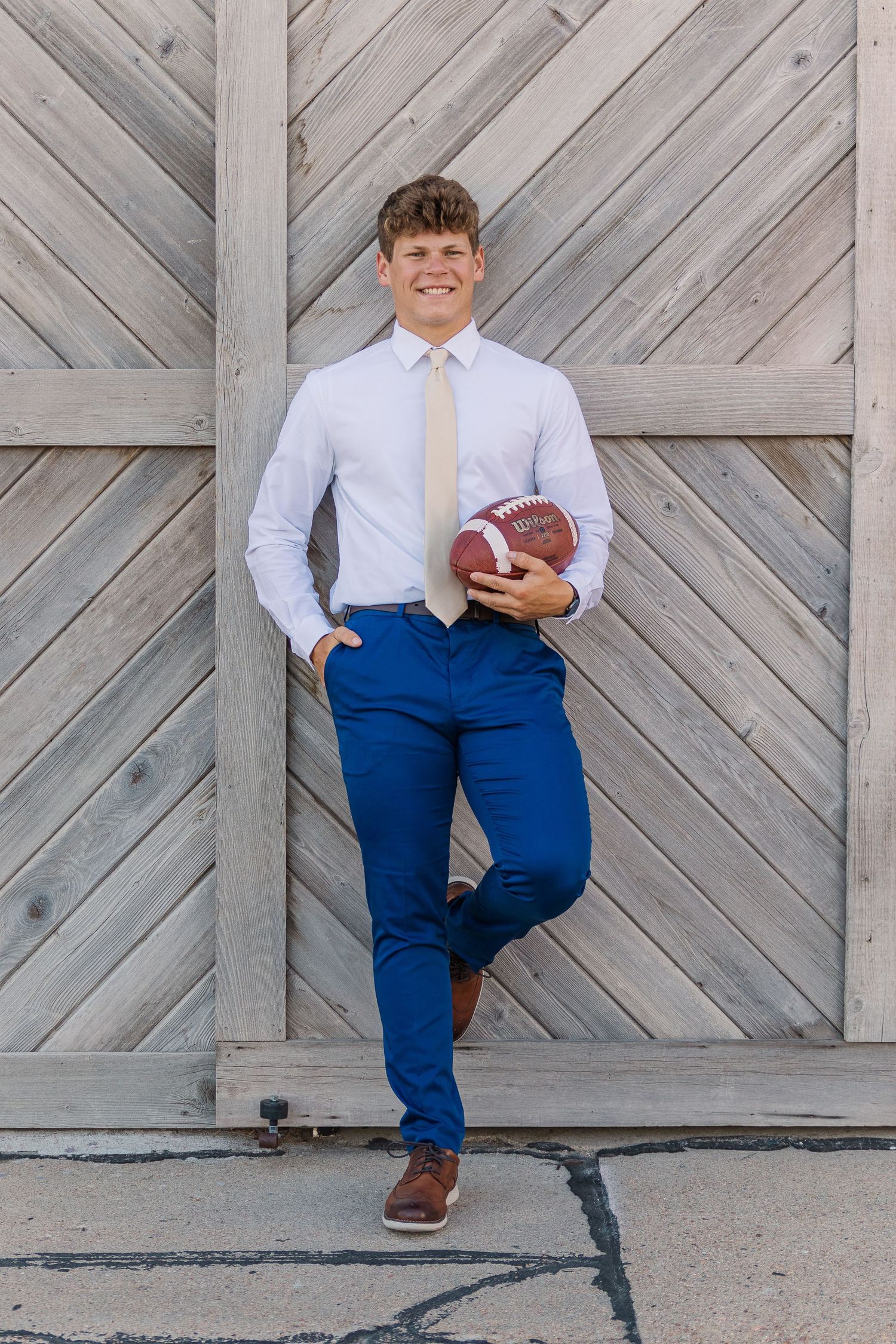 becky katzberg photography senior boy in dress pants, shirt and tie holding football