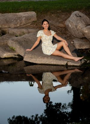 becky katzberg photography senior girl sitting on rock in yellow dress with reflection in water