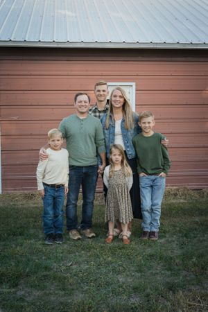 becky katzberg photography family photo in front of older brown barn wearing earth tone colors