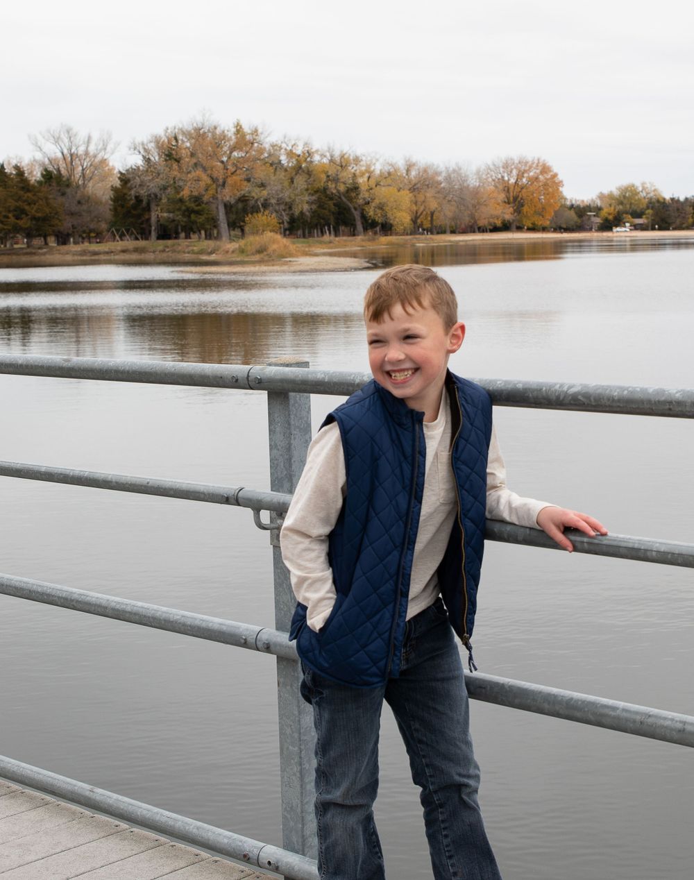 becky katzberg photography young boy on a dock by the water laughing and looking to the side