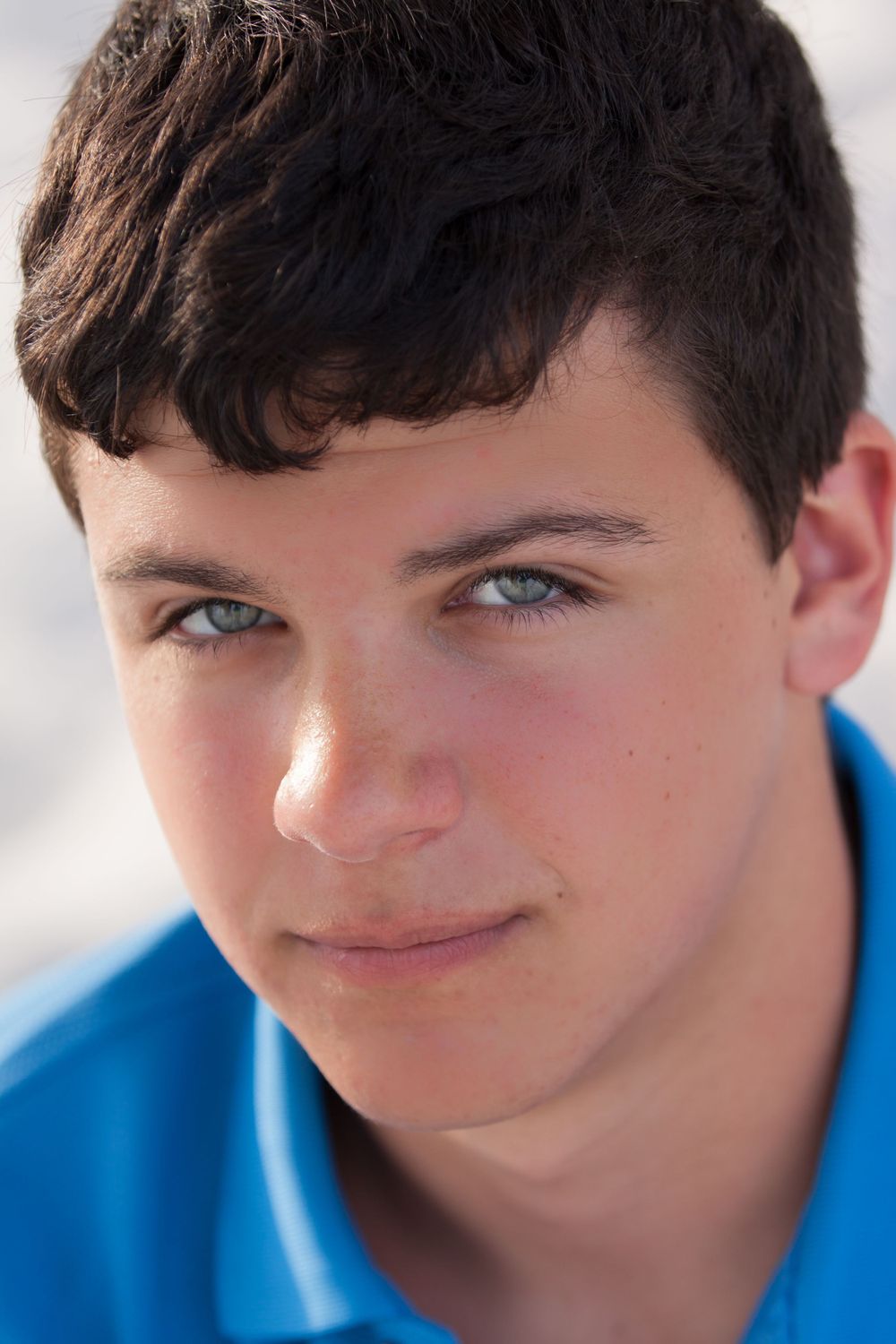A blue eyed senior boy gets his close up portrait taken on Pensacola Beach, Florida