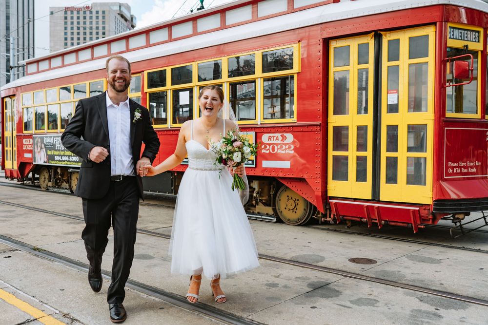 A couple runs together in front of a red streetcar on Canal Street.