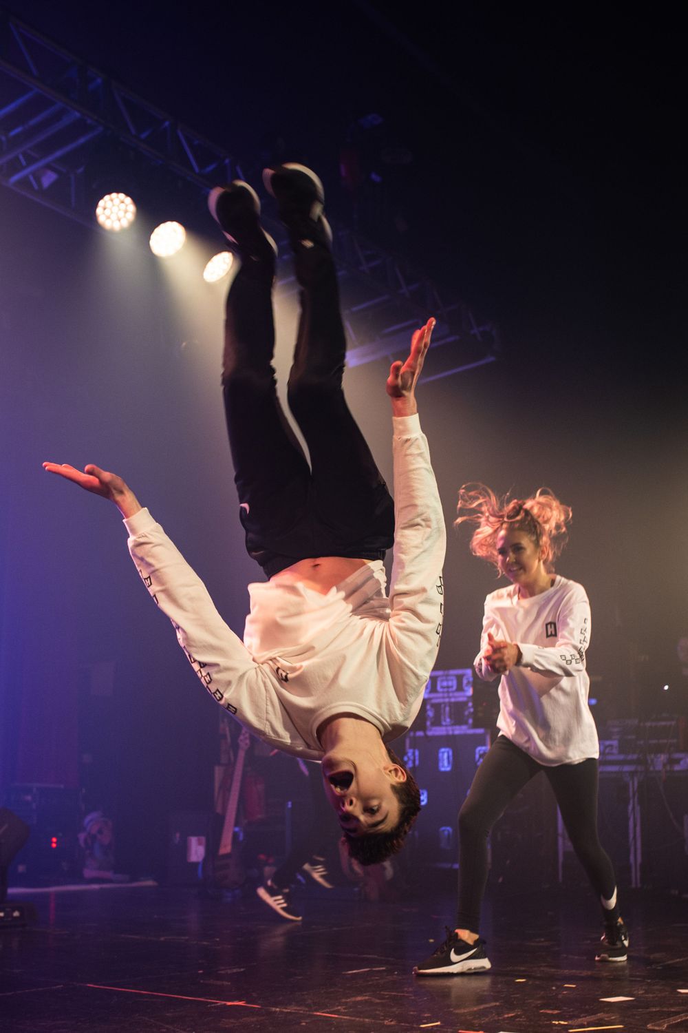 Dancers perform acrobatic moves in dramatic stage lighting at a performance venue.