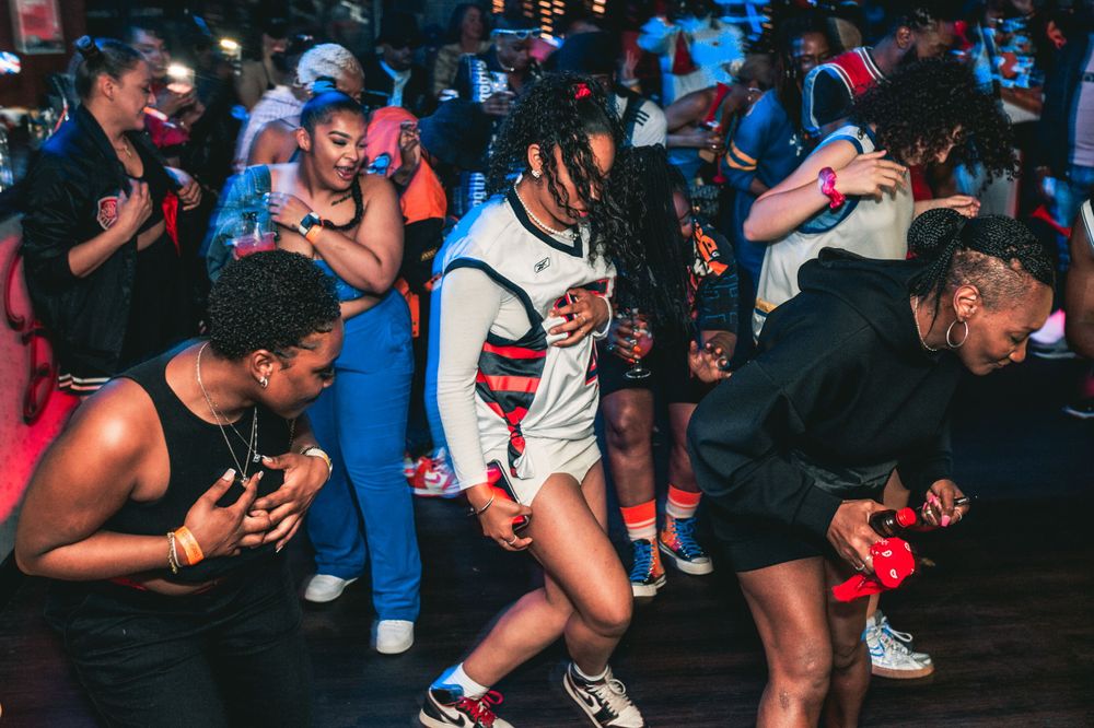 Crowd of dancers performing synchronized movements at an indoor event.