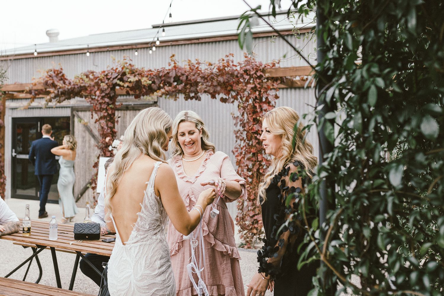 Rustic outdoor wedding venue with industrial metal building and natural landscaping.
