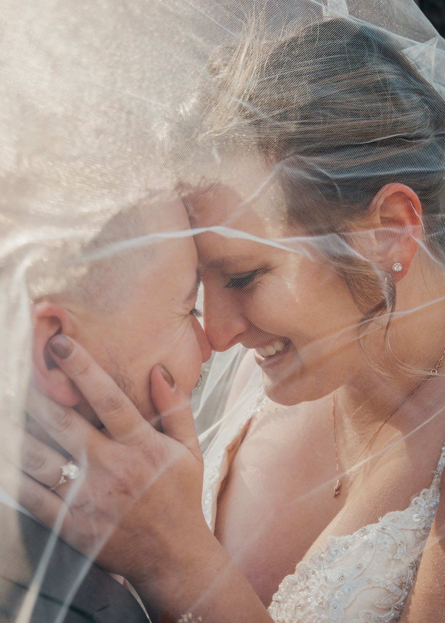 bride and groom cuddle close under veil