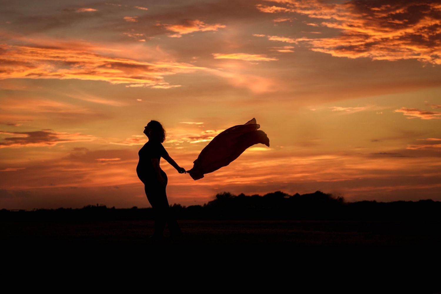 Maternity photography; woman throwing caution to the wind with a gorgeous sunset in Matagorda, TX.