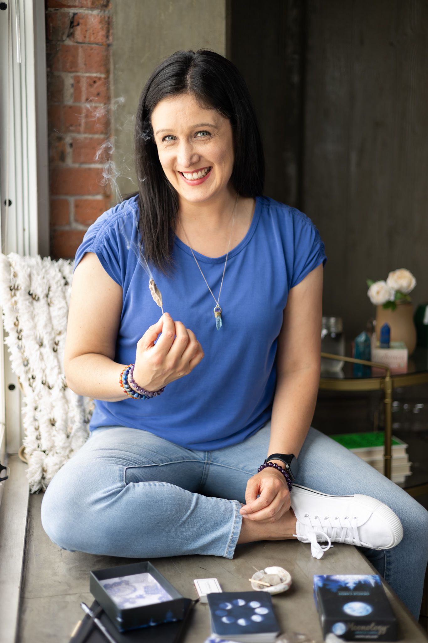 woman smiling at camera with sage cleansing smoke in hand smiling for personal branding photos in Seattle, WA