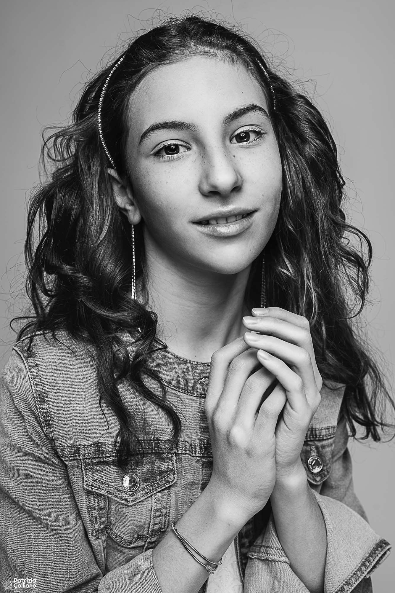 Black and white portrait of a person in denim jacket with curly hair and natural lighting.