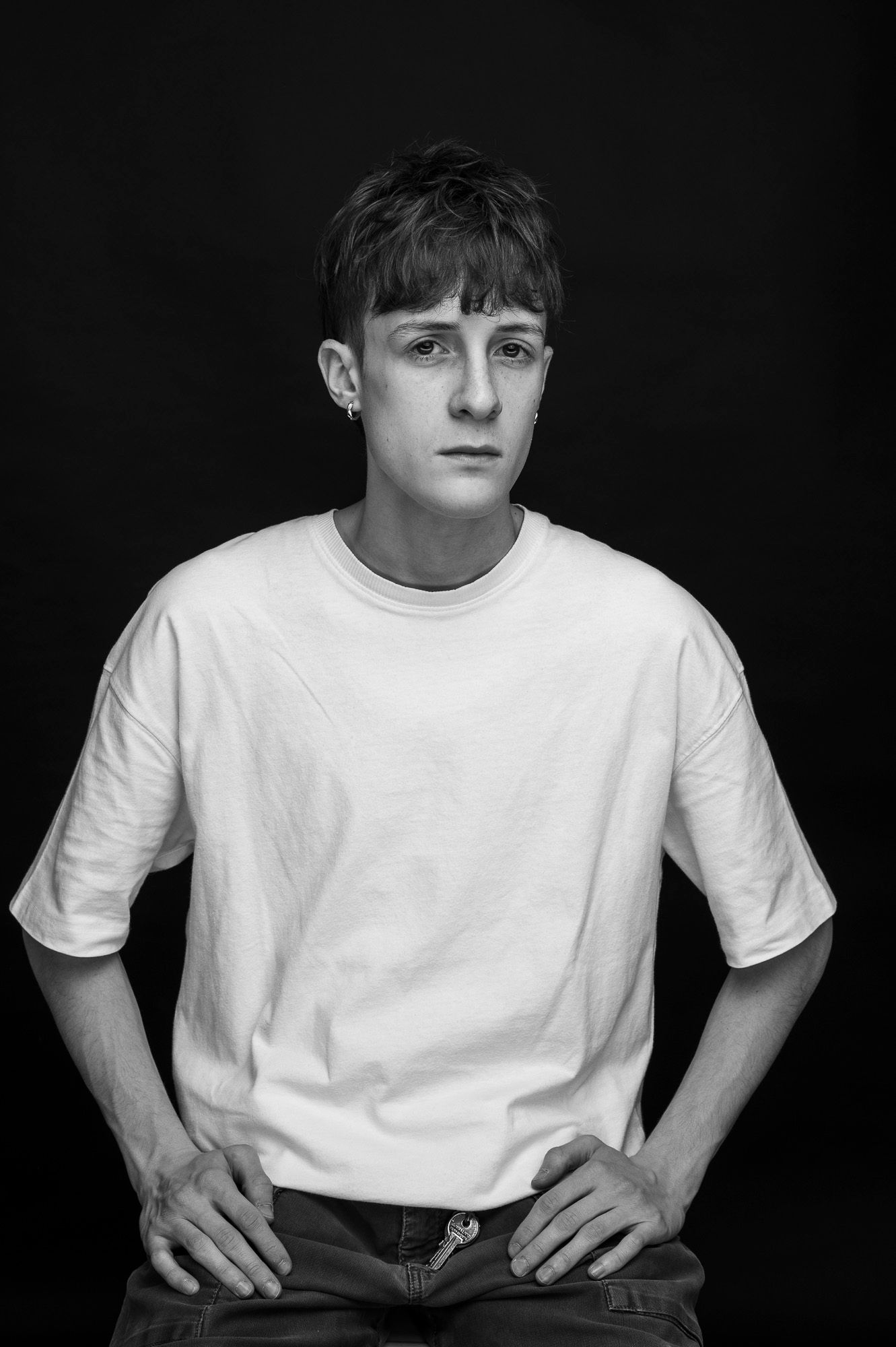 Dramatic monochrome studio portrait of a person wearing a casual white t-shirt and jeans.